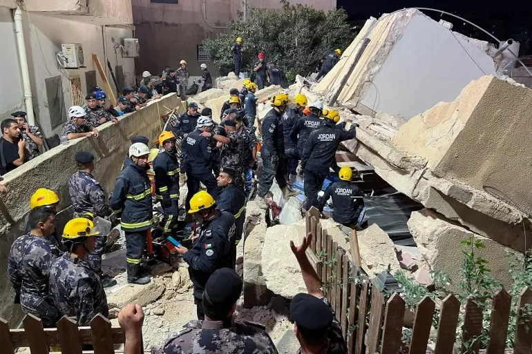 رجال دفاع مدني أردنيون في موقع انهيار مبنى سكني بإربد ليلاً