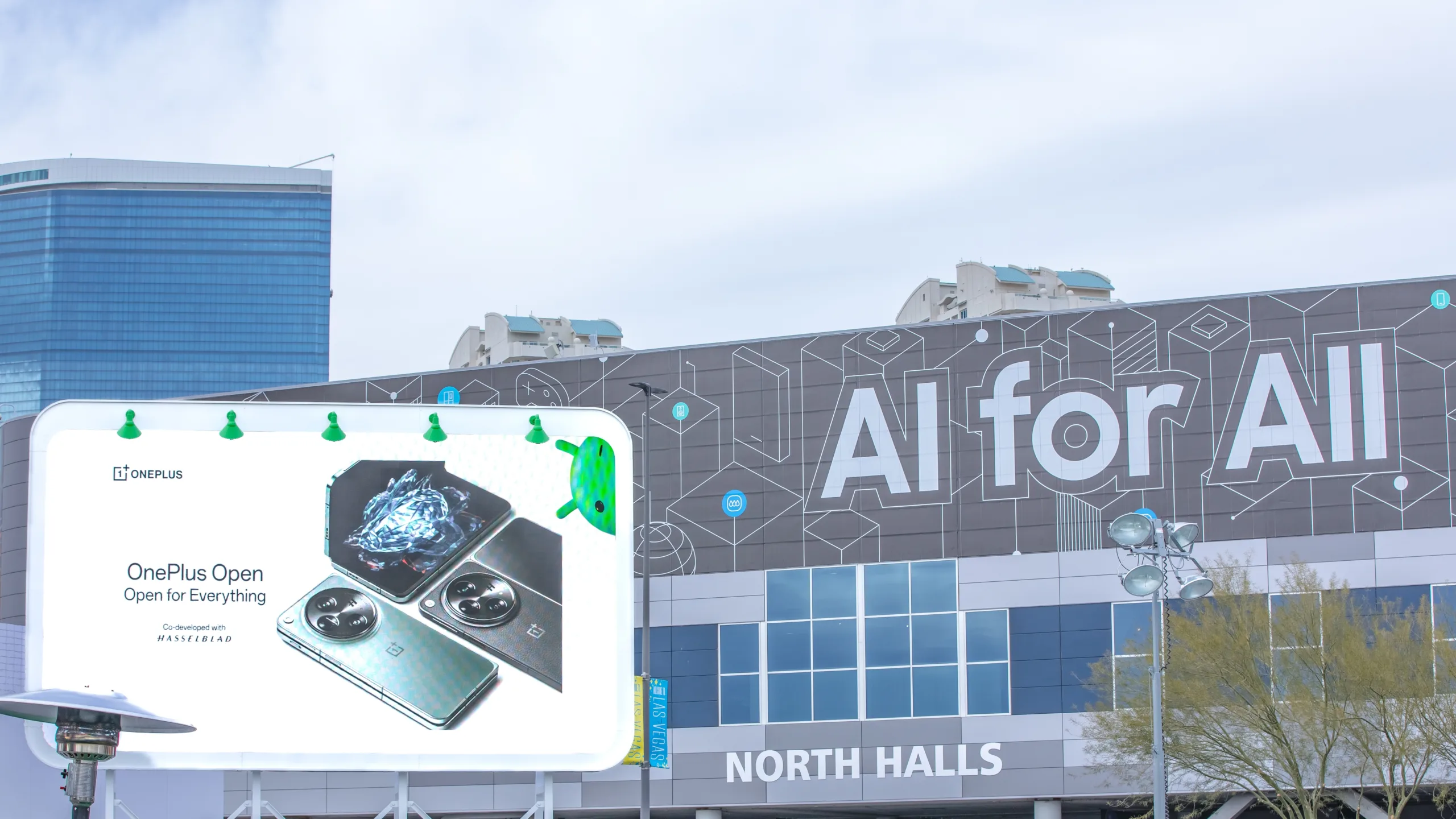 واجهة مركز مؤتمرات لاس فيغاس خلال معرض CES 2024، تظهر لافتة "AI for All" وإعلان لهاتف OnePlus Open.