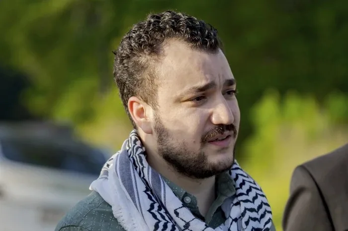 الناشط الفلسطيني محمود خليل يرتدي كوفية ويتحدث أمام وسائل الإعلام