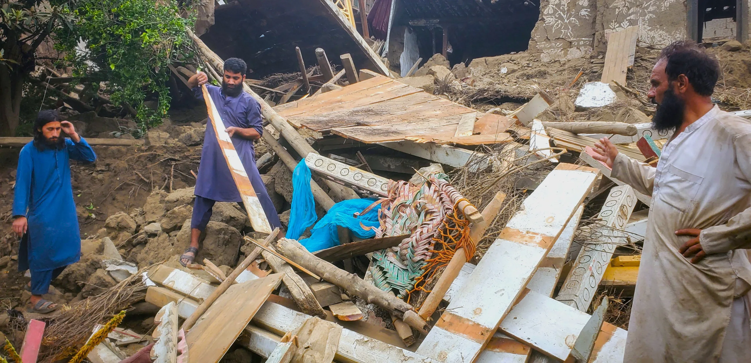 رجال يقفون وسط أنقاض مبنى منهار بعد زلزال أفغانستان