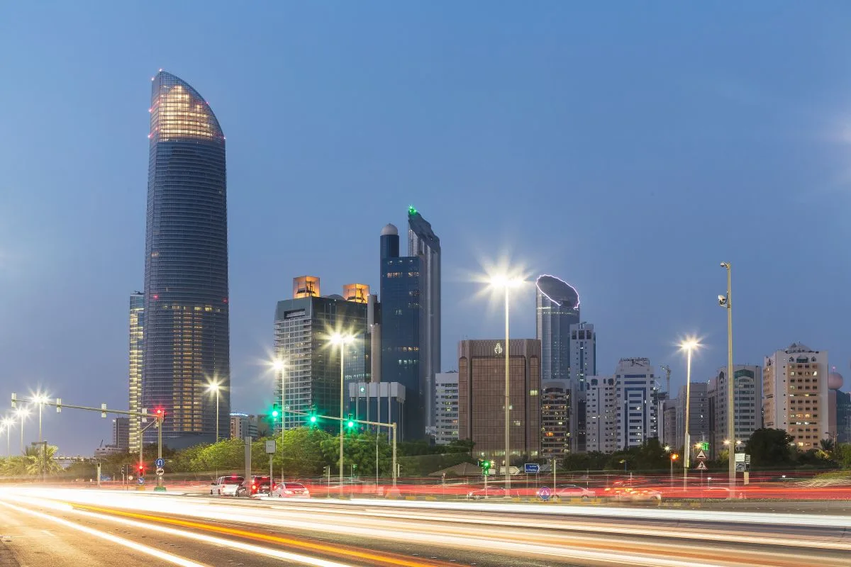 منظر سماء أبوظبي الليلي يظهر الأبراج الحديثة والشوارع المضاءة بحركة المرور والإشارات الضوئية
