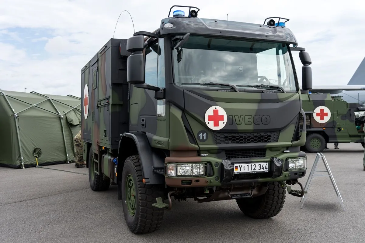 سيارة إسعاف عسكرية ألمانية من طراز إيفيكو مجهزة برموز الصليب الأحمر وخيمة طبية عسكرية في الخلفية