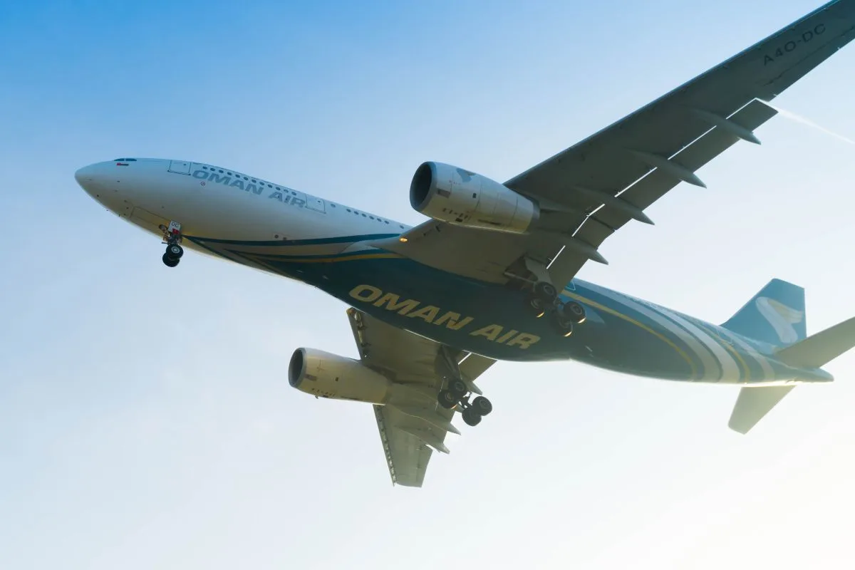 طائرة الخطوط الجوية العمانية تحلق في السماء بألوانها الأزرق والأخضر المميزة