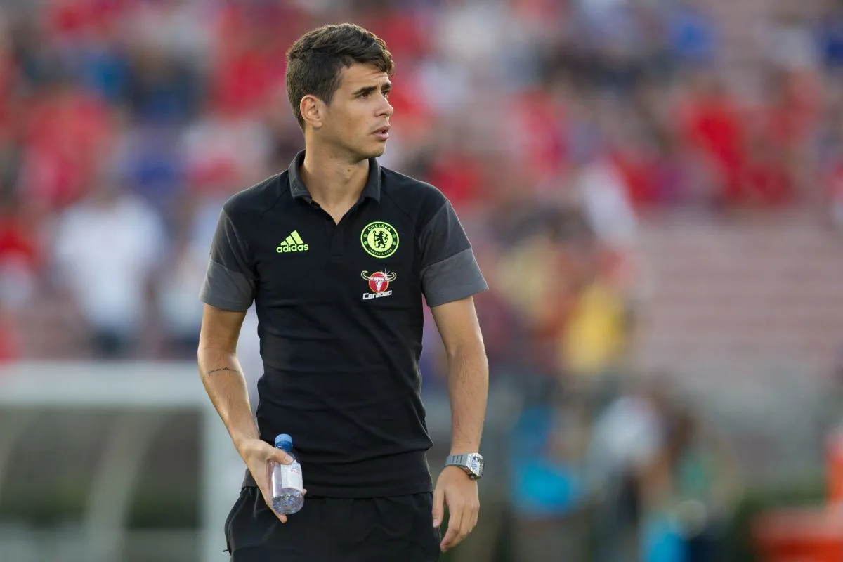 لاعب تشيلسي السابق أوسكار يقف على الملعب بملابس تقنية سوداء مع شعار النادي