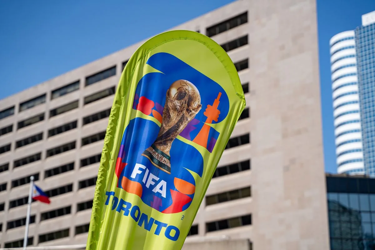 علم يحمل شعار كأس العالم فيفا بمدينة تورونتو أمام مبانٍ حديثة