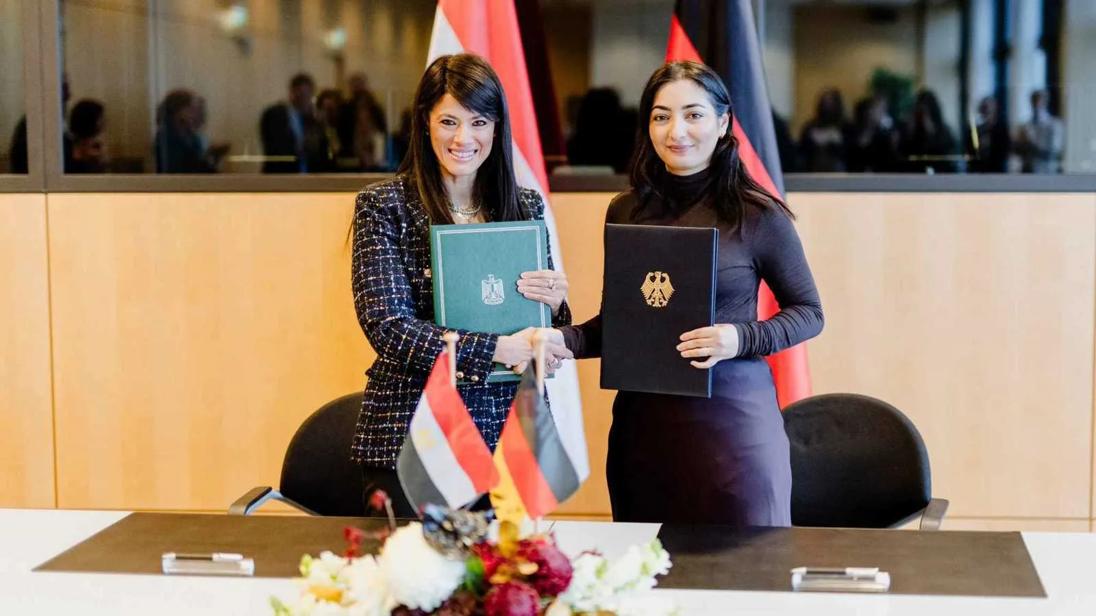 امرأتان توقعان اتفاقية دولية بين مصر وألمانيا أمام الأعلام الوطنية