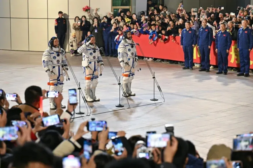 رواد فضاء صينيون بدلات الفضاء خلال حفل استقبال رسمي بحضور الجماهير والوفود الحكومية