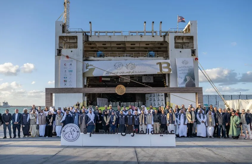 مجموعة من المسؤولين والمتطوعين أمام سفينة مساعدات إماراتية في ميناء.