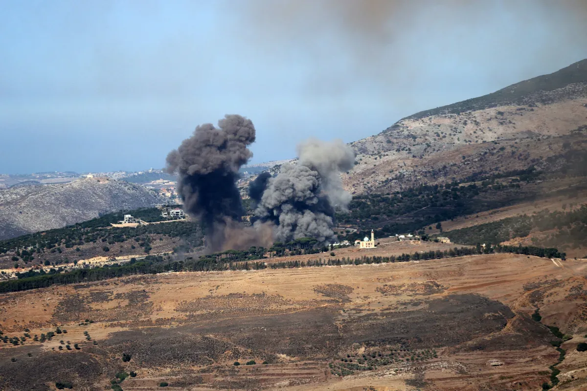 تصاعد أعمدة دخان كثيفة جراء انفجارات في منطقة جبلية قرب قرية ومسجد.