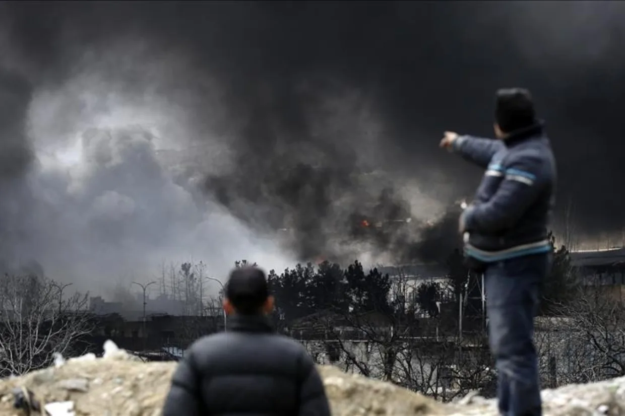 رجلان يشاهدان تصاعد سحابة ضخمة من الدخان الأسود الكثيف جراء حريق كبير أو انفجار